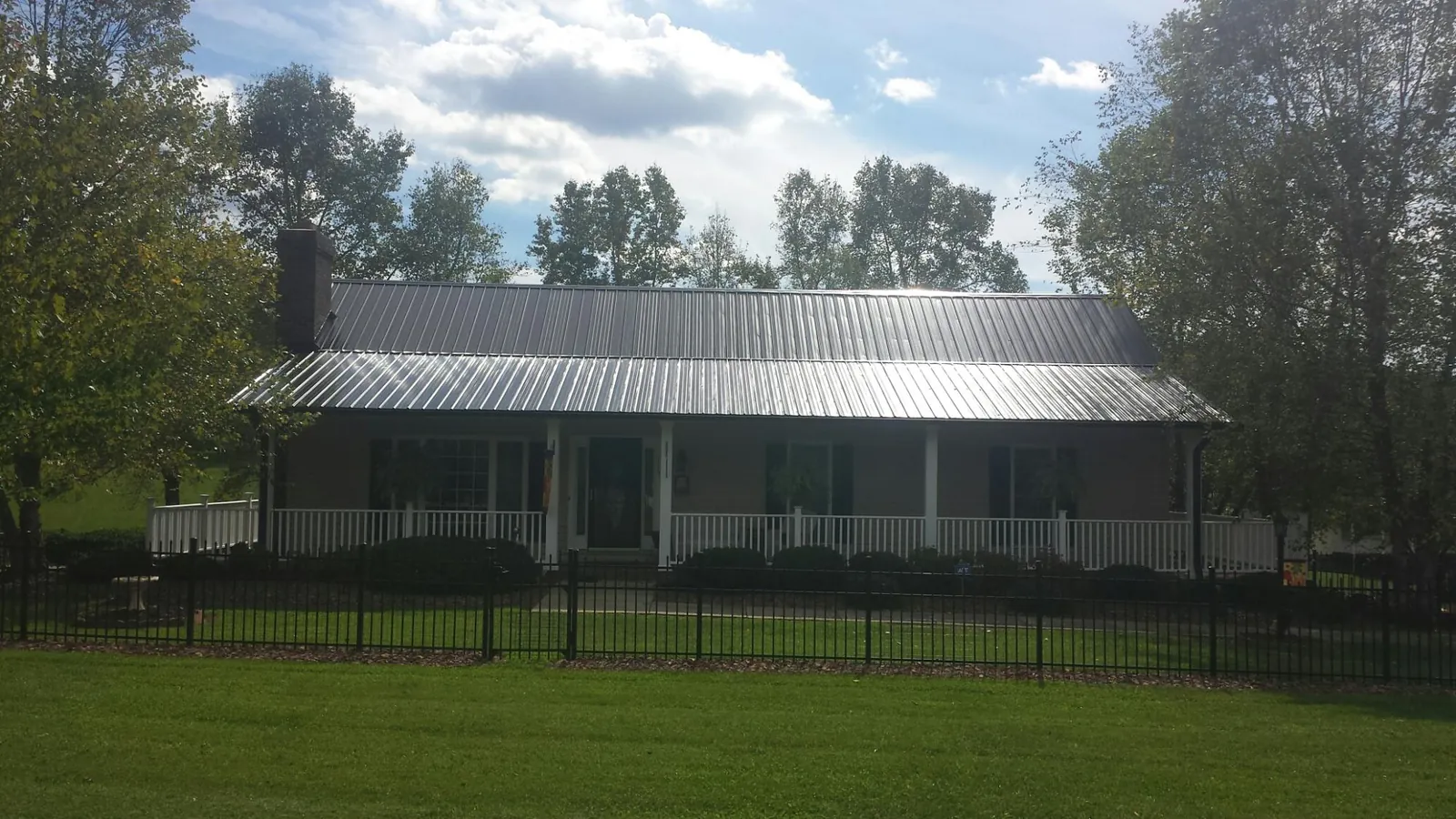Gray metal roof on a brick ranch with a full width front porch — Gutter Guard Installation work by our crew in North Salt Lake